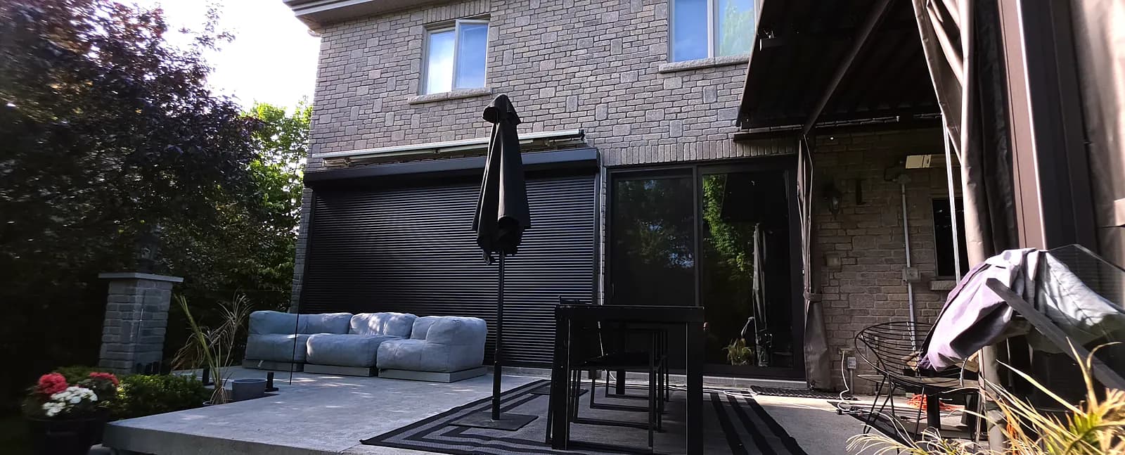 Black security roller shutters on the patio doors of a backyard in Boucherville