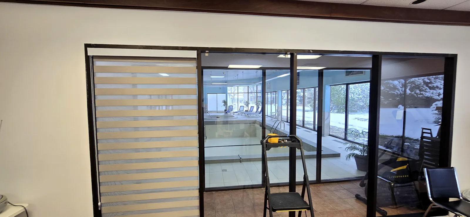 Stores alternés (zébrés) sur un mur vitré qui donne sur une piscine intérieure, Dorval