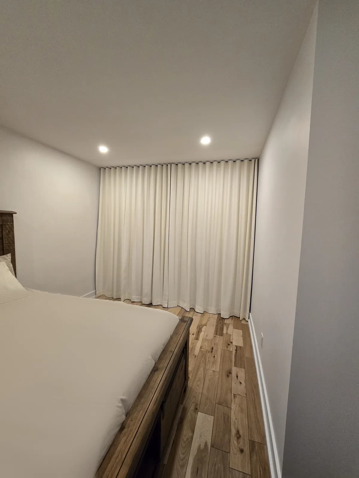 Full-height blackout curtains at the far end of a bedroom, Montreal